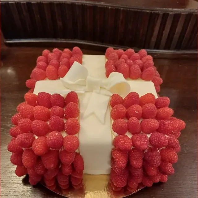 Torte in Geschenkform mit weißer Fondantschleife und frischen Himbeeren vom Café am Markt in Jena