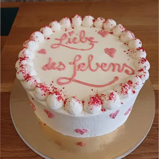Weiße Torte mit rosafarbenem Schriftzug und Herzen zum Valentinstag oder Jahrestag vom Café am Markt in Jena