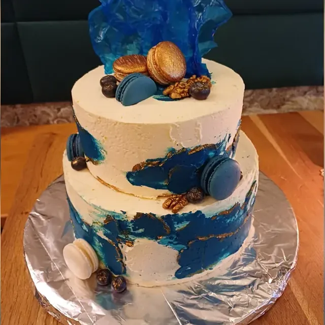Zweistöckige Torte in Blau und Gold mit Macarons und Zuckersegel vom Café am Markt in Jena