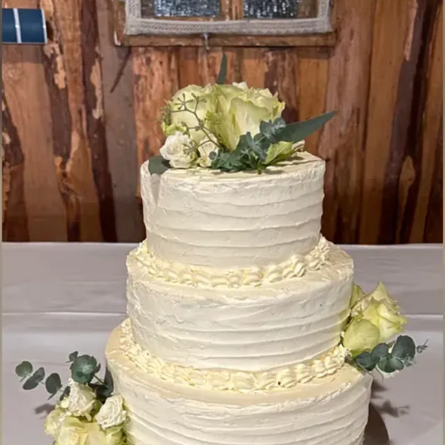Dreistöckige cremeweiße Hochzeitstorte mit Rosen und Eukalyptus aus der Patisserie in Jena