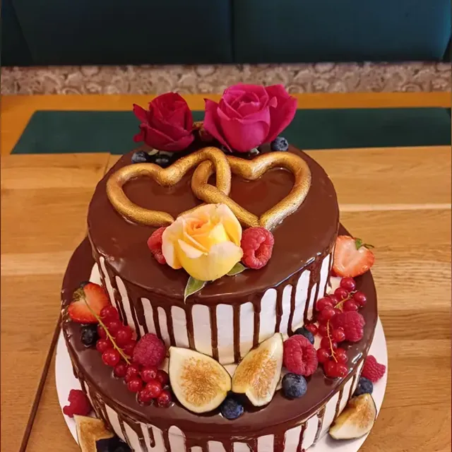 Zweistöckige Festtorte mit Schokoladenglasur, goldenen Marzipanherzen und Rosen zur Hochzeit in Jena