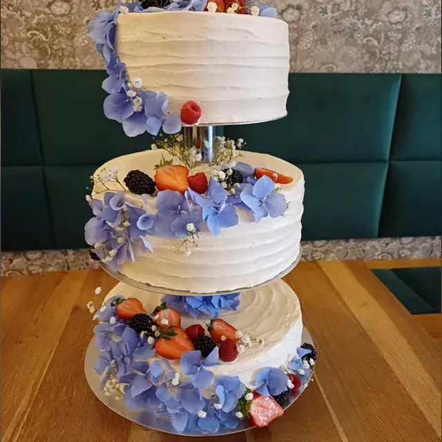 Dreistöckige Hochzeitstorte mit blauen Hortensien, Beeren und Schleierkraut aus der Patisserie in Jena