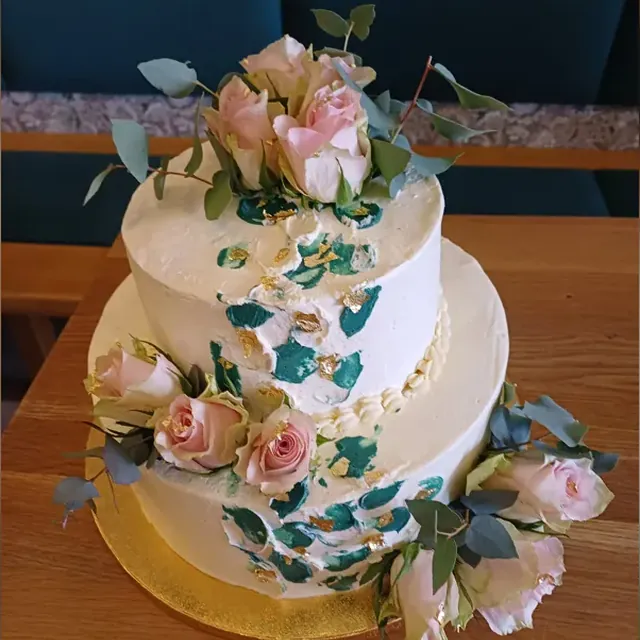 Zweistöckige Hochzeitstorte mit grünen Buttercreme-Pinselstrichen, Blattgold und Rosen in Jena