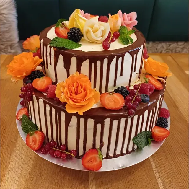 Zweistöckige Drip-Torte mit orangefarbenen Rosen, Beeren und Marzipanrosen vom Café am Markt in Jena