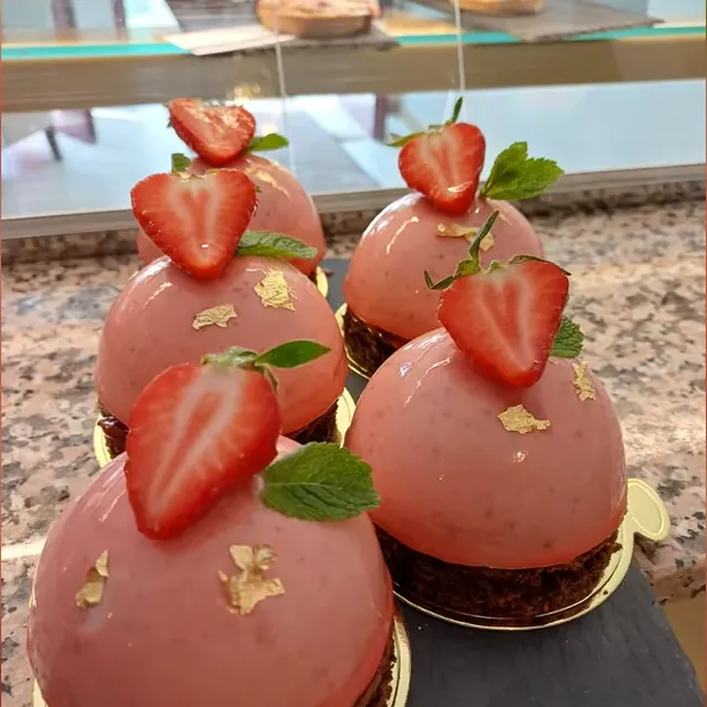 Glasierte Erdbeermousse-Kuppeln mit Blattgold und frischer Erdbeere aus der Patisserie in Jena