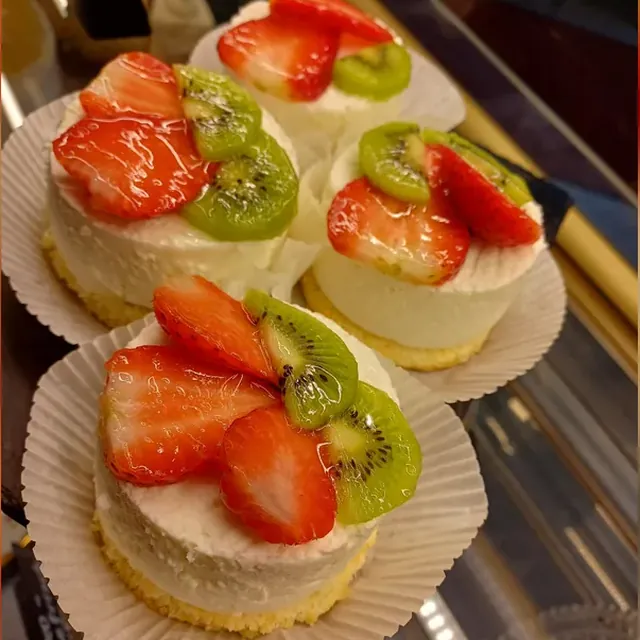 Käsesahne-Törtchen mit Erdbeer- und Kiwischeiben in der Theke des Café am Markt in Jena