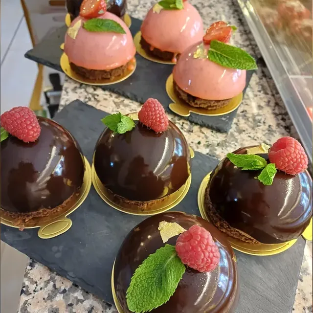 Glasierte Mousse-Törtchen mit Erdbeer- und Schokoladenglasur in der Theke des Café am Markt in Jena