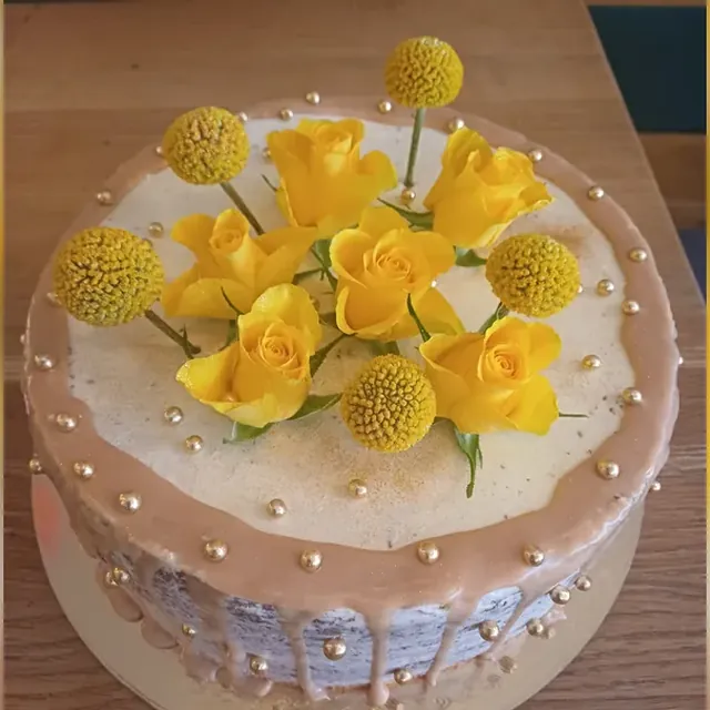 Karamell-Drip-Torte mit gelben Rosen, Craspedia und goldenen Zuckerperlen aus der Patisserie in Jena